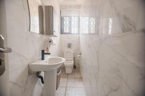 een witte badkamer met een wastafel en een toilet bij OG Residence in Accra