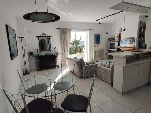 Saronida Art Apartment في Saronida: مطبخ وغرفة معيشة مع طاولة وكراسي زجاجية
