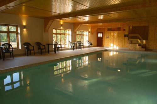 a large swimming pool with tables and chairs in a building at Duddings Country Cottages in Minehead