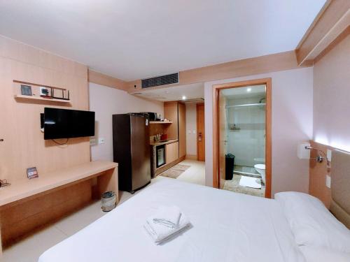 a room with a bed and a television and a bathroom at Flat Cullinan Brasília SL in Brasilia