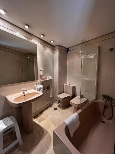 a bathroom with a sink and a tub and a toilet at Apartamentos Olano C.B. in Madrid