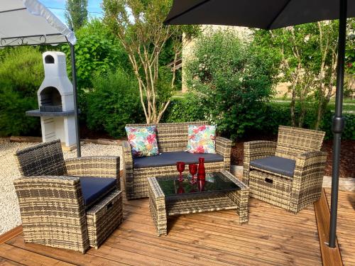 a patio with wicker chairs and a table with an umbrella at La Tuilerie Grange (Adults only gite) with two en-suite double bedrooms in Le Bugue