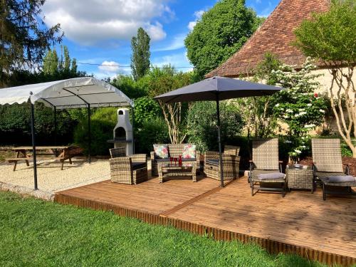 a wooden deck with chairs and an umbrella at La Tuilerie Grange (Adults only gite) with two en-suite double bedrooms in Le Bugue