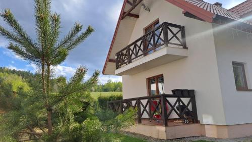 Casa blanca con balcón y árbol en Domki Oaza Spokoju Berezka, en Berezka