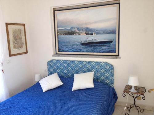 a bedroom with a blue bed with a painting of a boat at Villa mit Whirlpool und phantastischer Aussicht in Capoliveri