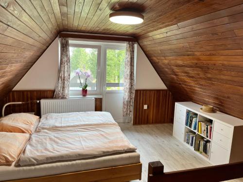 a attic bedroom with a bed and a window at Chata Hůrka in Horní Planá