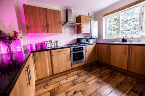 a kitchen with wooden cabinets and a wooden floor at Spacious London Home - Garden, BBQ & Free Parking, Sleeps 8 in London