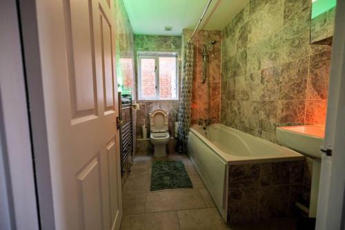 a bathroom with a tub and a toilet and a sink at Pristine Relocation House in London