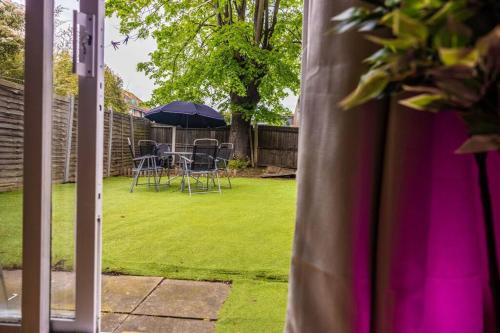 a patio with a table and chairs and an umbrella at Spacious London Home - Garden, BBQ & Free Parking, Sleeps 8 in London