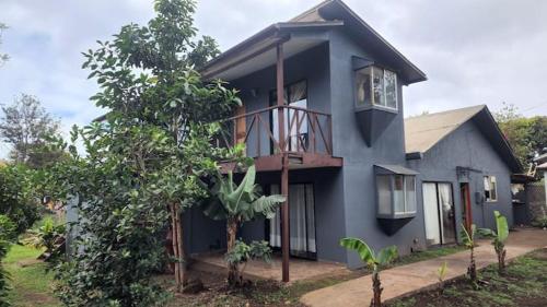 uma casa azul com uma varanda e uma árvore em marari rapa nui em Hanga Roa
