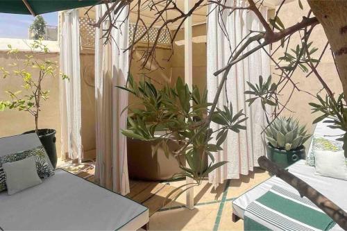 a balcony with potted plants and a table and a window at Dar Vevé - Design, style & relax in Dar el Bacha in Marrakesh