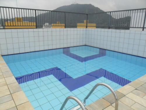 una gran piscina con azulejos azules en un edificio en Dom Pedro 26, en Guarujá