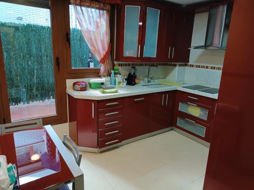 a kitchen with red cabinets and a large window at Karmelo junto al metro in Bilbao