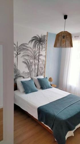 une chambre avec un grand lit avec des oreillers bleus dans l'établissement Appartement Terre et Mer, à Hyères