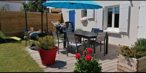 um pátio com uma mesa, cadeiras e um guarda-sol em Maison proche océan em Saint-Hilaire-de-Riez
