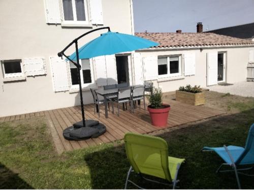 um pátio com uma mesa, cadeiras e um guarda-sol em Maison proche océan em Saint-Hilaire-de-Riez