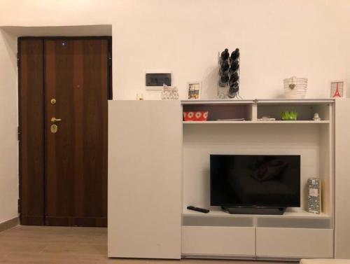 una sala de estar con TV en un centro de entretenimiento blanco en Appartamento nel Borgo, en Orte