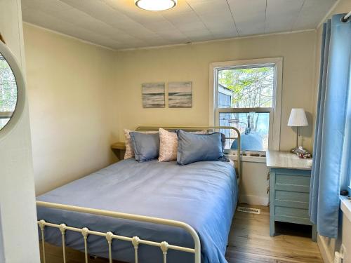 a bedroom with a bed with blue sheets and a window at Peaceful Lily Pad Cottage In Hubbards in Hubbards