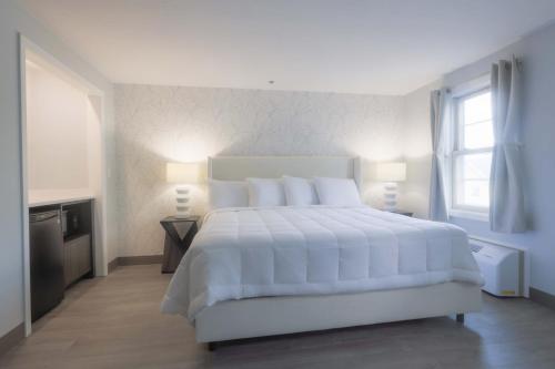 a white bedroom with a large white bed and a window at Westborough Inn in Westborough