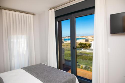 a bedroom with a bed and a sliding glass door at Apartamentos Villa Zoila Nigrán in Nigrán