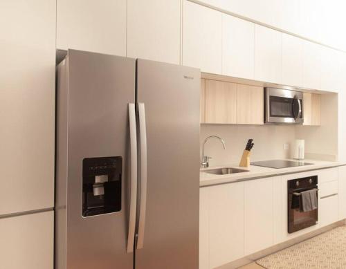 um frigorífico de aço inoxidável numa cozinha com armários brancos em Apartamento una habitación DLX em Echeverría