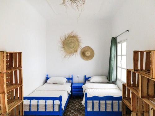 2 camas en una habitación con paredes azules y blancas en Kasbari House, en Taghazout