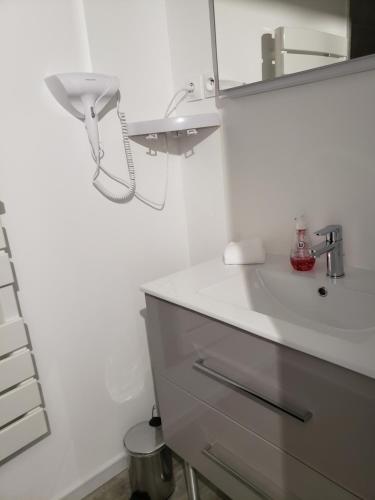 een witte badkamer met een wastafel en een spiegel bij Studio 6 in Le Boupère