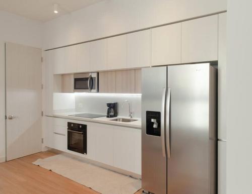 uma cozinha branca com um frigorífico de aço inoxidável em Junior Suite DLX Aeropuerto em Echeverría