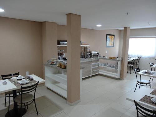 Cerrado Hotel LTDA في كامبو غراندي: مطبخ وغرفة طعام مع طاولات وكراسي