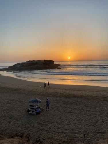 a group of people standing on a beach at sunset at Kasbari House in Taghazout