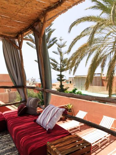 a bed on a balcony with a palm tree at Kasbari House in Taghazout