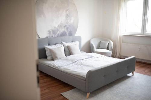 a white bedroom with a bed and a chair at Zentral Bahnhof Apartment# Ntfx# in Halle an der Saale