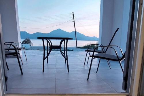 a table and chairs on a porch with a view of the ocean at Bay-dream 3 in Adamantas