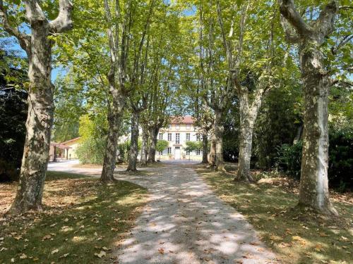 a tree lined road with a house in the background at La Bourdette - Elegantes Herrenhaus im Boutique Stil in Daumazan-sur-Arize