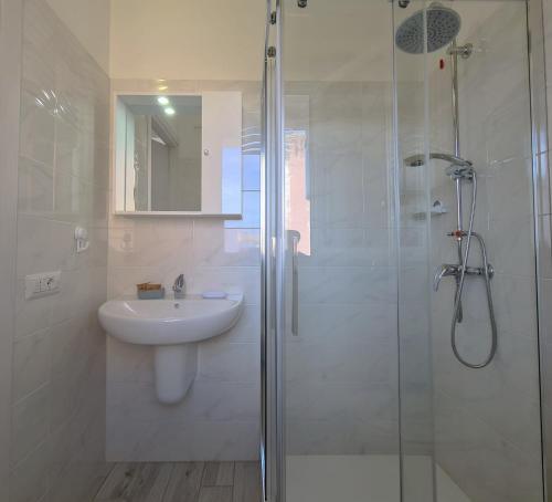 a white bathroom with a sink and a shower at Civico 14 Apartment 3 in Monserrato