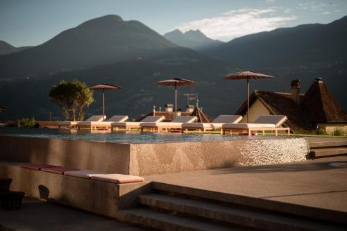 a swimming pool with lounge chairs and umbrellas at Hotel Muchele in Postal