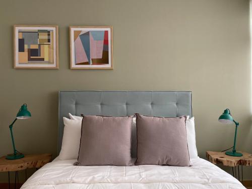 een slaapkamer met een bed met kussens en 2 lampen bij New apartments in building with pool, rooftop and gym in Condesa in Mexico-Stad