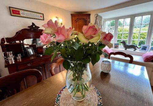 un jarrón de rosas rosas sentado en una mesa en Vine Cottage en Farnham