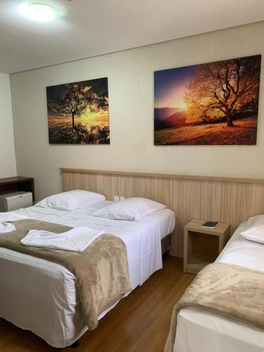 two beds in a room with two posters on the wall at Hotel San Lucas in Gramado