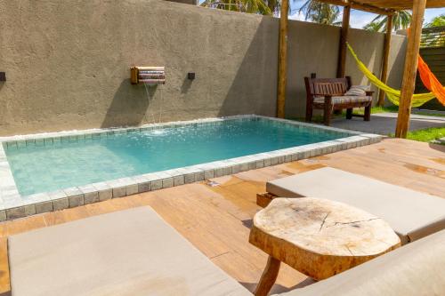 a swimming pool with a table and a swing at Nareia Casa Milagres in São Miguel dos Milagres