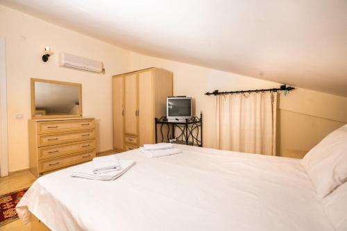 een slaapkamer met een wit bed en een televisie bij Lovely Flat near Beach with Shared Pool in Kalkan in Kalkan