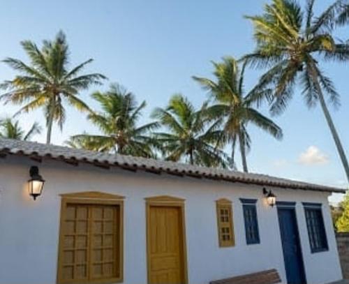 a white house with palm trees in the background at Pousada Vila Sol Maior in Guarapari