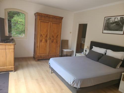 ein Schlafzimmer mit einem großen Bett und einem Holzschrank in der Unterkunft Villa Mycènes in Garéoult