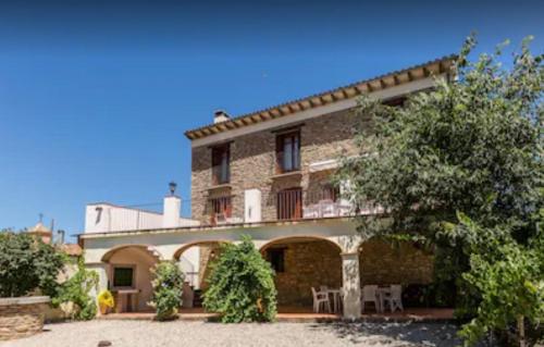 a large brick house with a patio and trees at Casa Joan de Fontsagrada in Fontsagrada