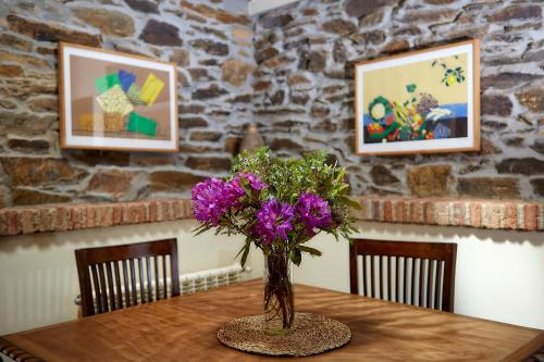 a table with a vase of purple flowers on it at La Era De Somao in Somado