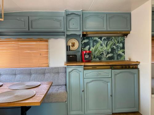 a kitchen with green cabinets and a table at Przyczepa Kempingowa Zefirek in Jastarnia