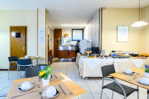 a restaurant with tables and chairs and a kitchen at Hotel Anna Siena Nord in Siena