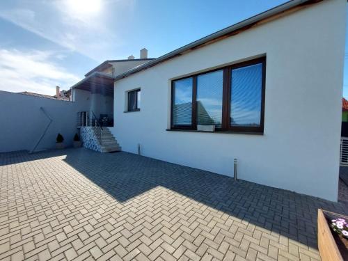a white house with a brick driveway at Prázdninový dům Sorada in Rohatec