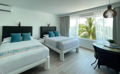 1 dormitorio con 2 camas, mesa y ventana en Suite Brisas Cancun, en Cancún