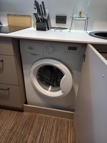 a washing machine in a kitchen with a counter at Zvejnieku apartamenti in Roja